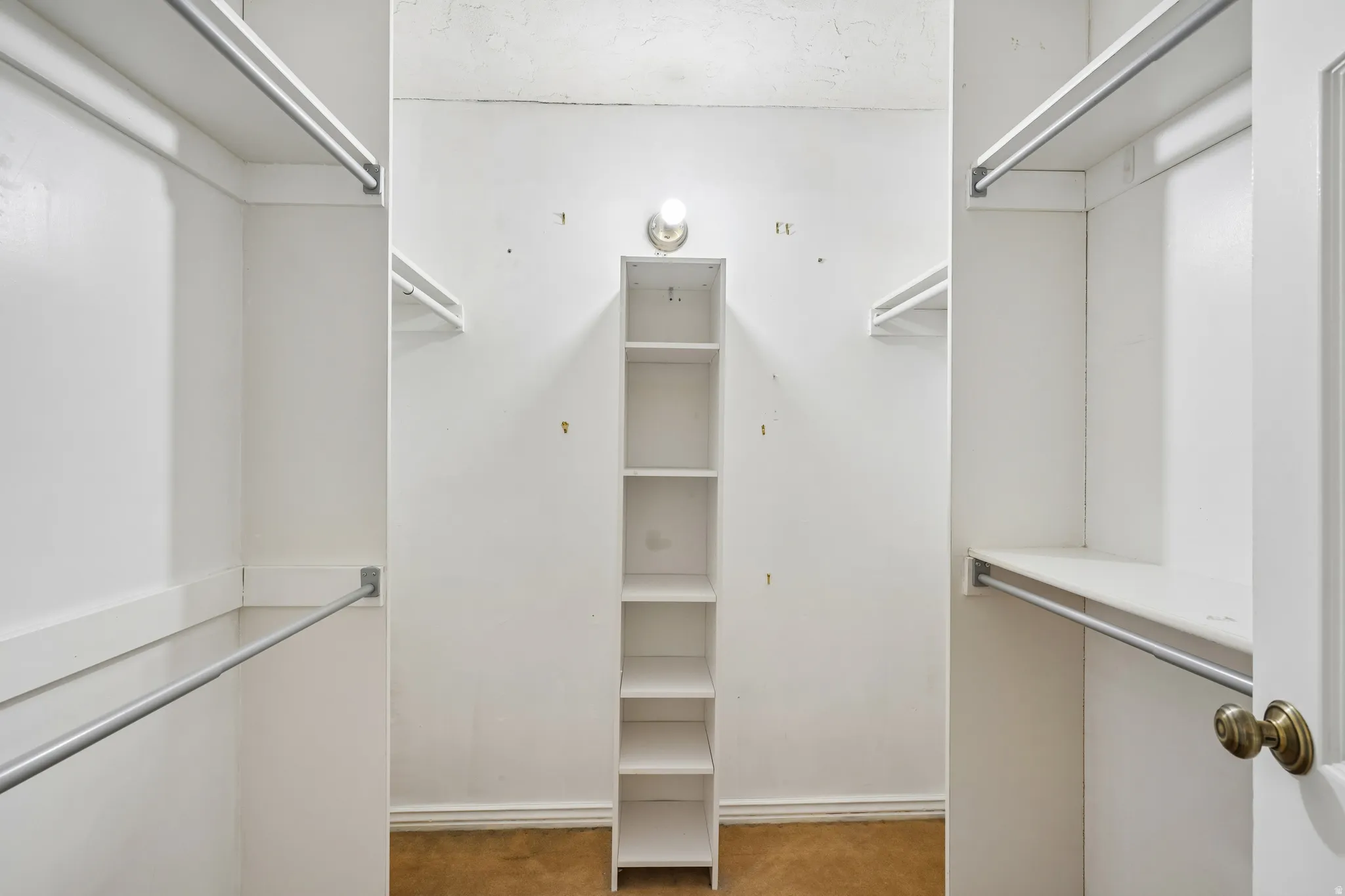 Walk-in closet featuring built-in shelving, multiple hanging rods, and white painted walls