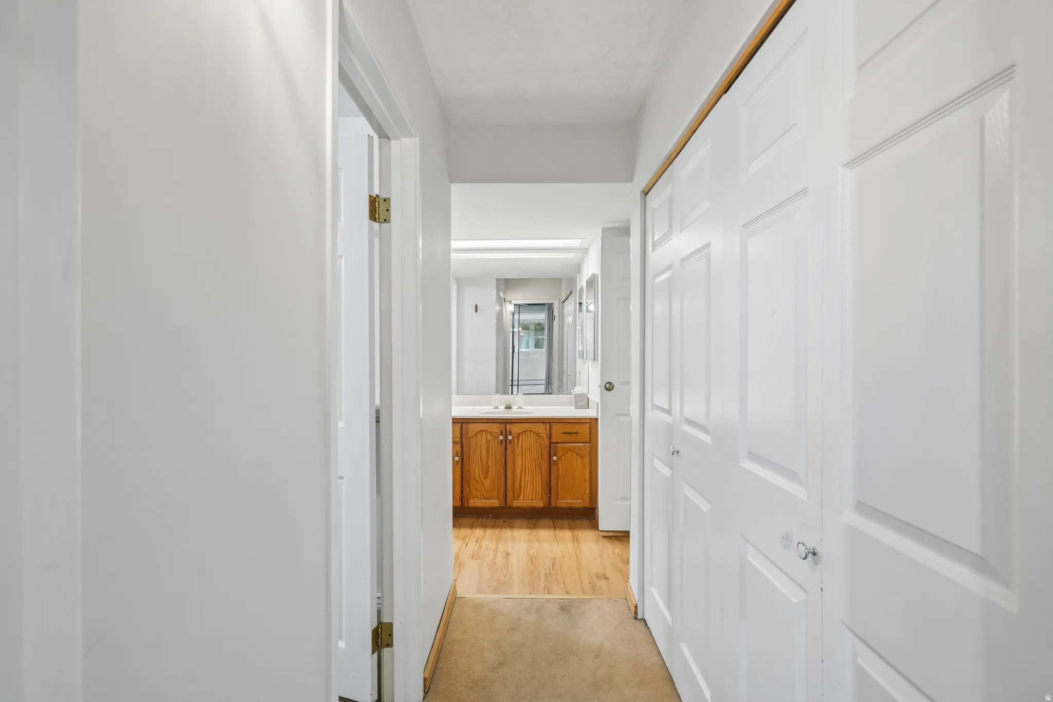 Hallway with bi-fold closet doors and wood-finish flooring