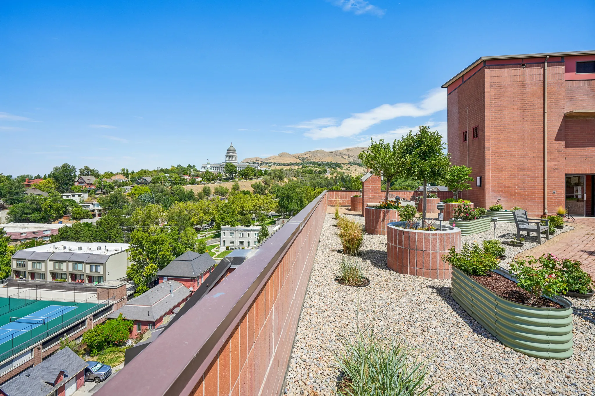 Rooftop terrace with pea gravel flooring, brick planters, and corrugated metal garden beds