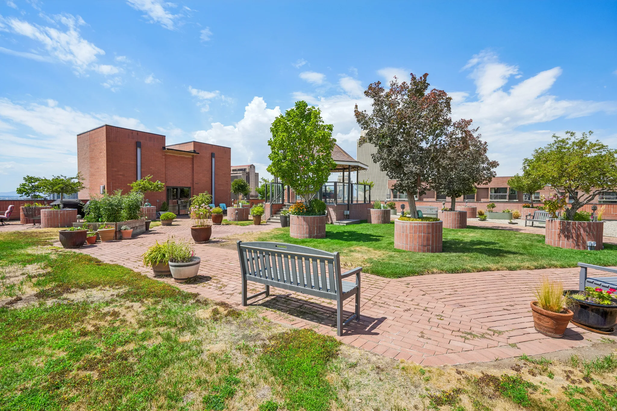 Expansive outdoor patio area featuring a brick walkway, manicured grass, and raised planters
