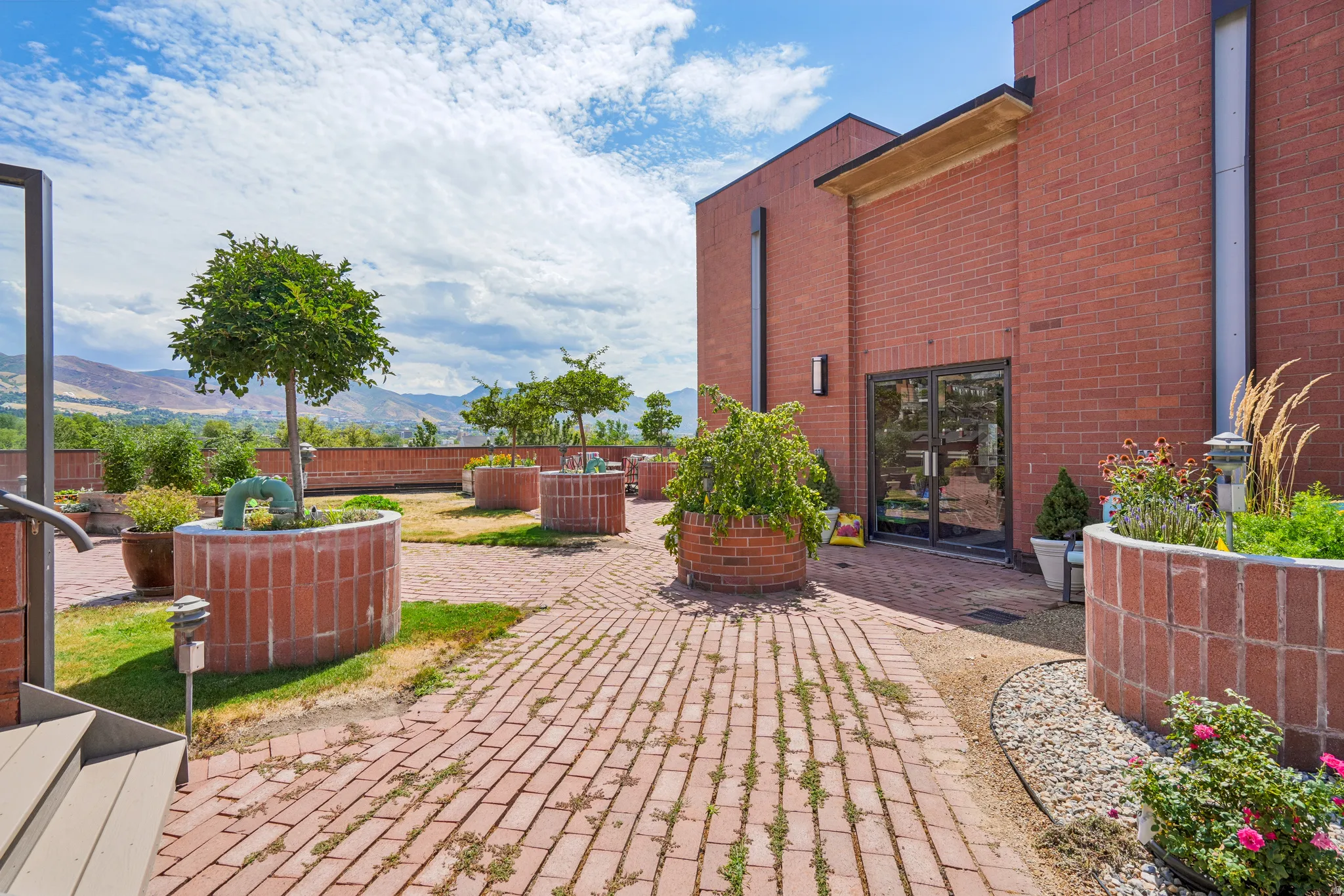 Expansive outdoor patio featuring brick pavers and integrated brick planters