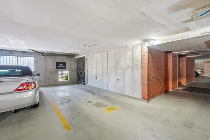 Secure parking garage with concrete flooring, exposed concrete walls, brick accents, and integrated lighting