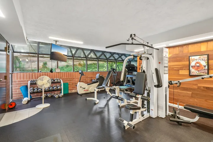 Dedicated fitness area featuring rubber flooring and wood-paneled accent wall