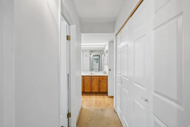 Hallway with bi-fold closet doors and wood-finish flooring