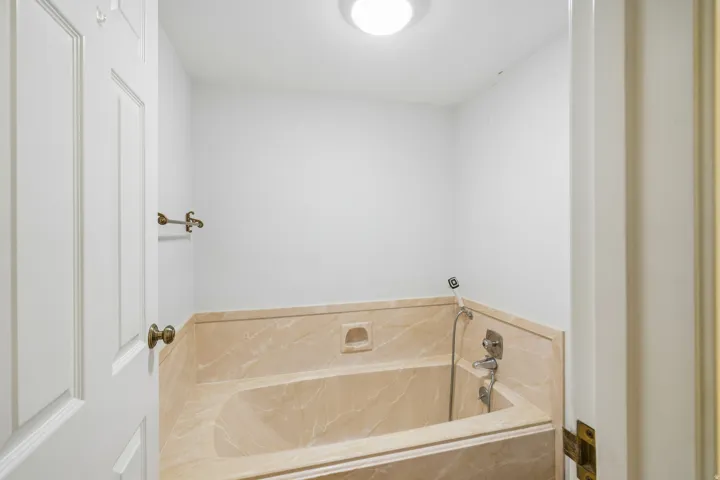 Recessed bathtub with integrated tiled surround, featuring a handheld shower fixture