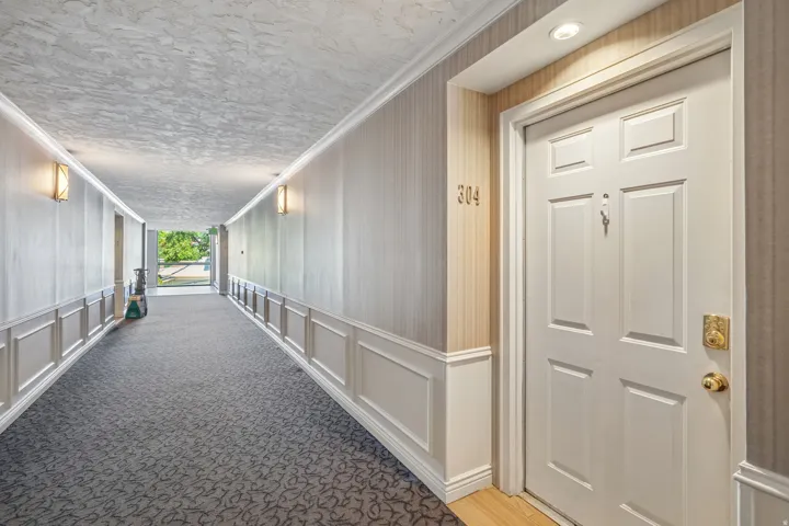 Hallway entry featuring white paneled wainscoting, textured wallpaper, and recessed lighting
