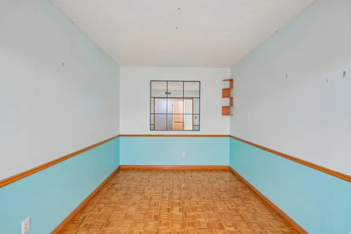 Room featuring parquet flooring and two-tone wall treatment with wood trim
