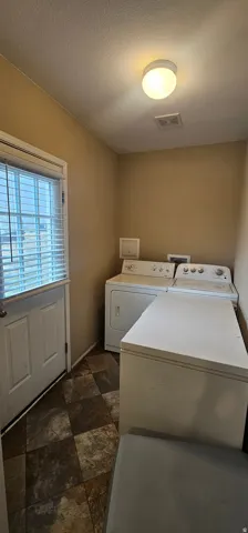Dedicated utility space featuring checkerboard flooring, a side-by-side appliance setup, and an exterior access door with integrated blinds