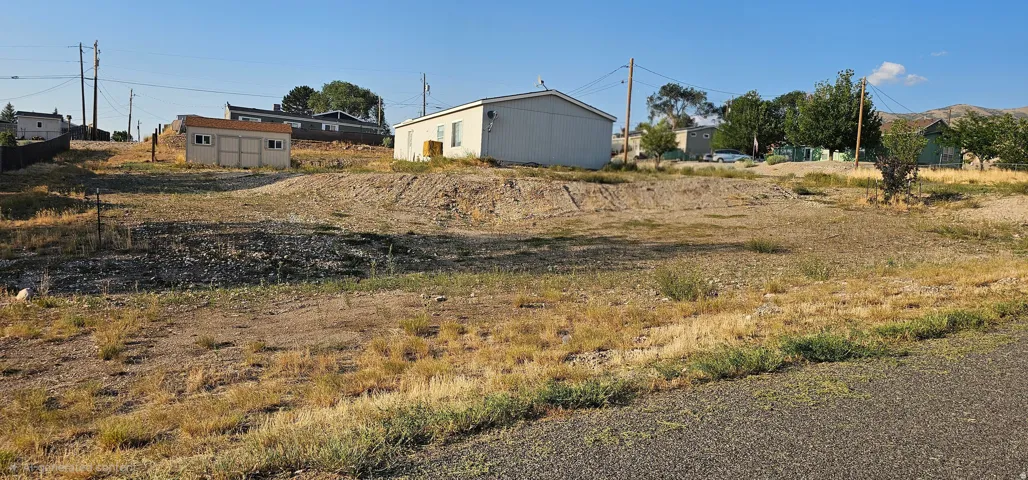 Expansive lot featuring a sloped terrain, visible road frontage, and distant mountainous backdrop
