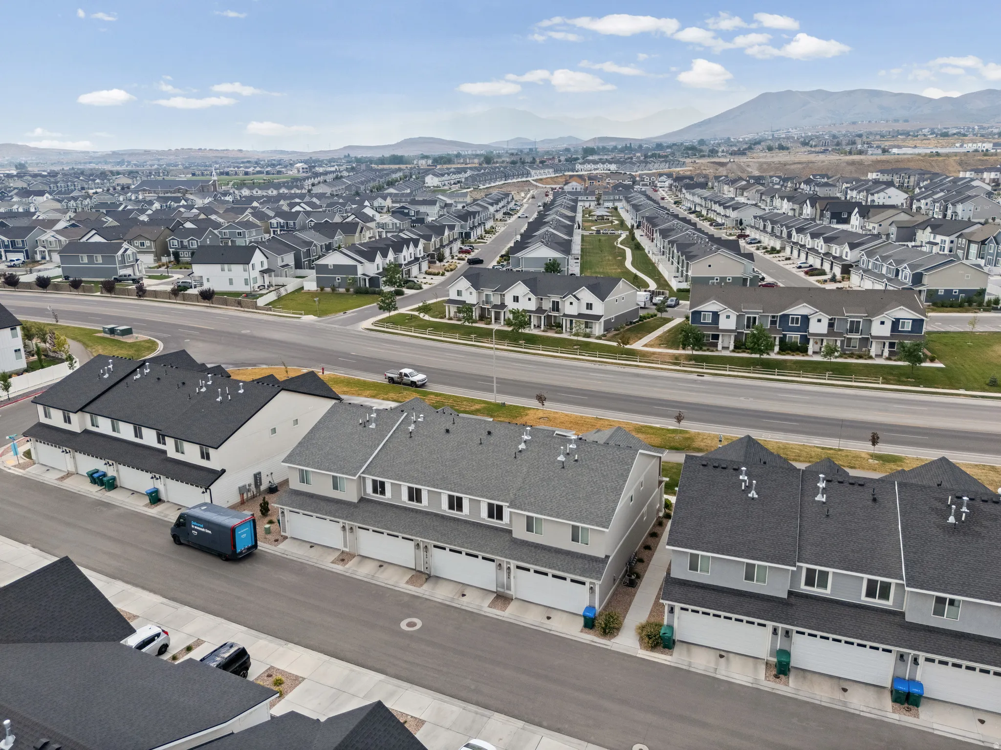 Expansive residential development featuring multiple rows of detached homes and townhomes with dark shingle roofs, light-colored facades, and integrated garages