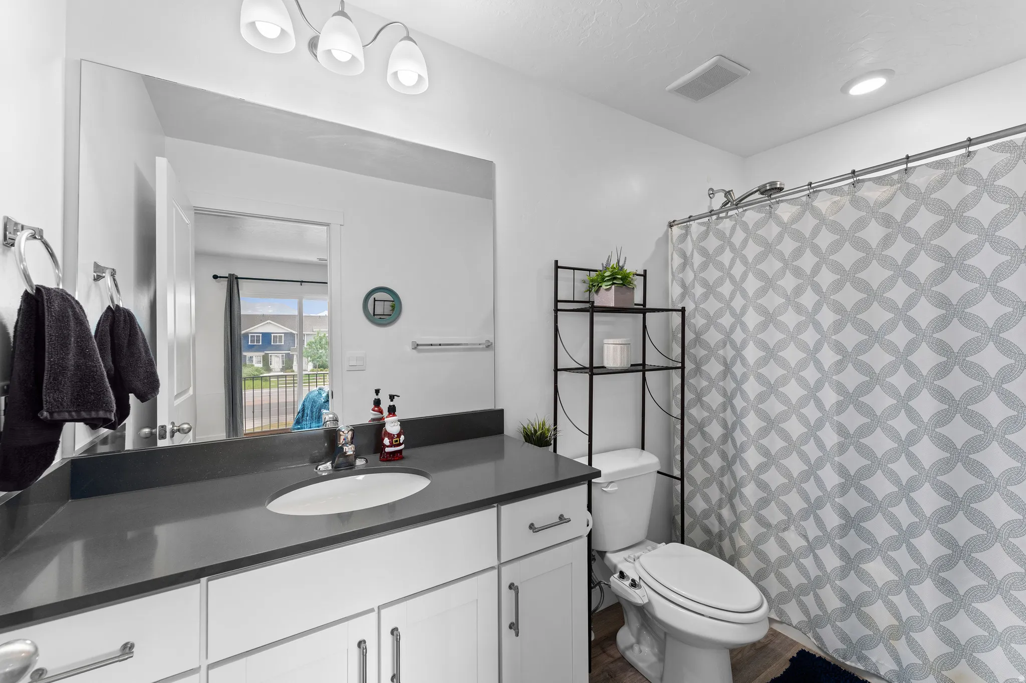Contemporary bathroom featuring a single vanity with a dark countertop, white cabinetry with silver hardware, a built-in shower, and recessed lighting