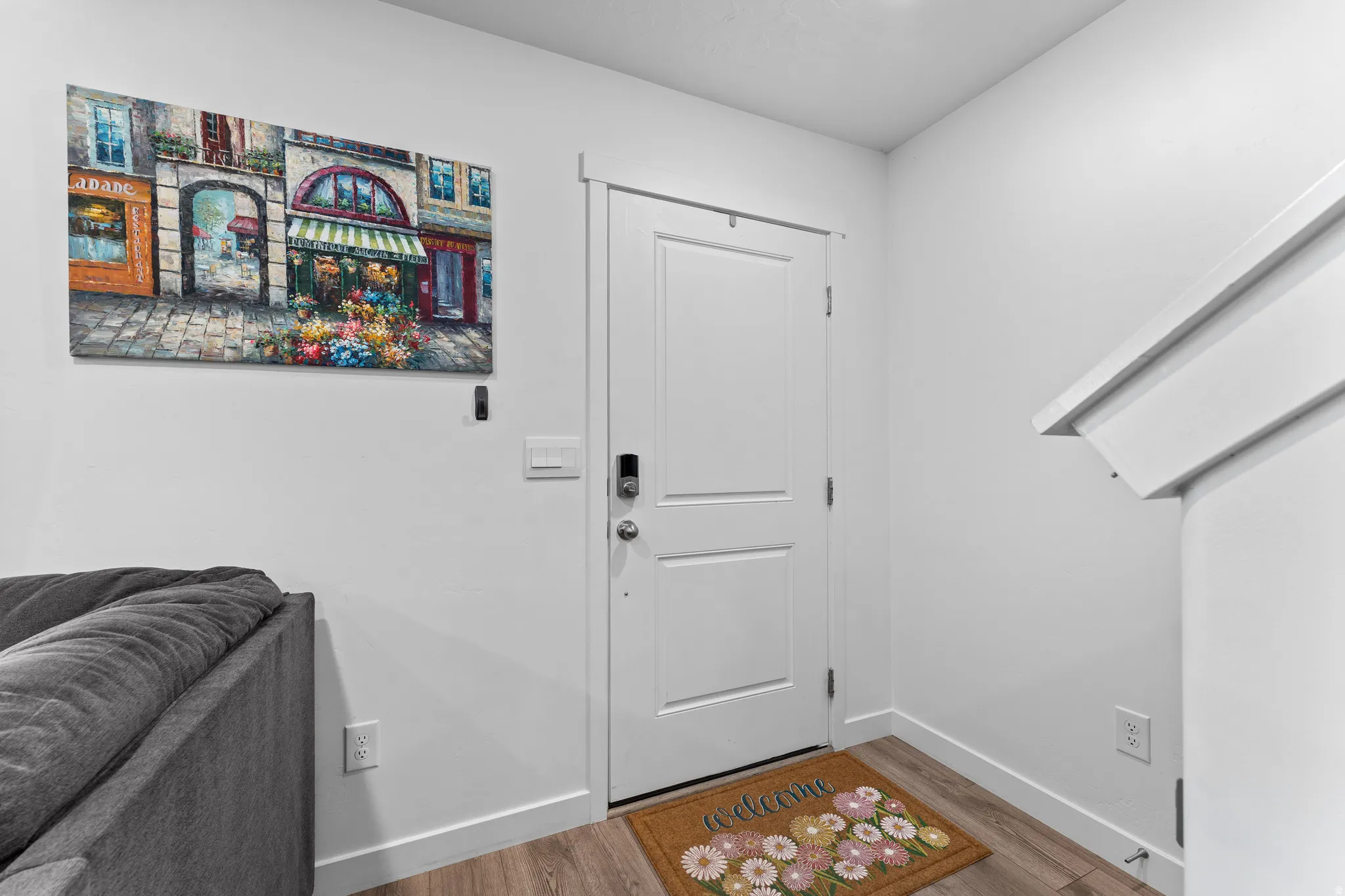 Entryway featuring a white paneled door with a digital lock, wood-finish flooring, and white baseboards