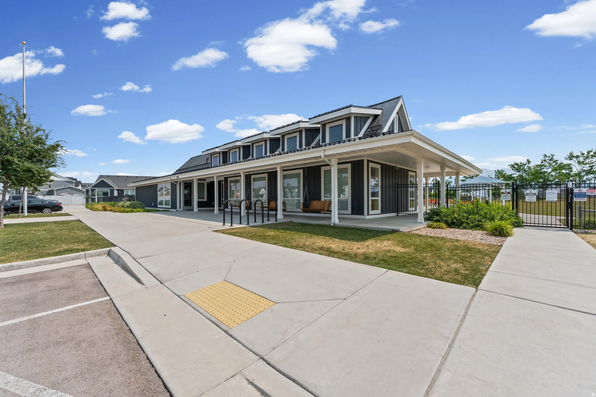 Building exterior featuring dark siding, white trim, multiple windows, a covered porch, and a peaked roofline