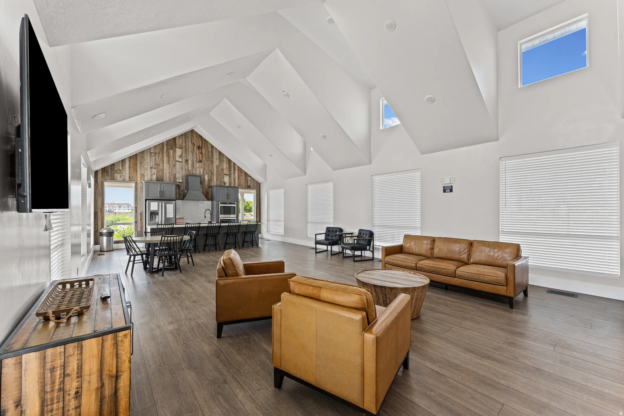 Spacious open-concept interior featuring vaulted ceilings, wood-finish flooring, and a full kitchen with dark cabinetry and a central island