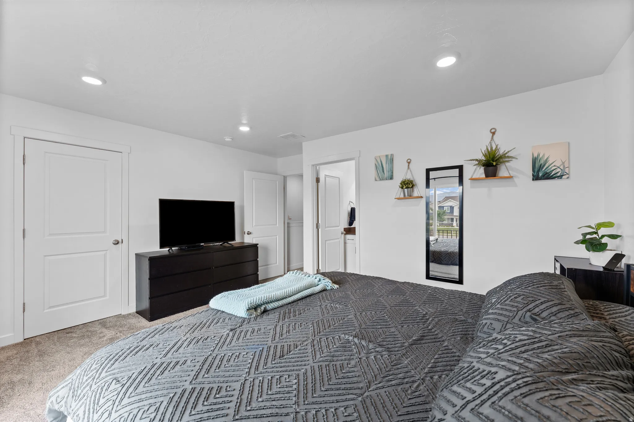 Recessed lighting illuminates the space, featuring white walls and neutral-toned carpet