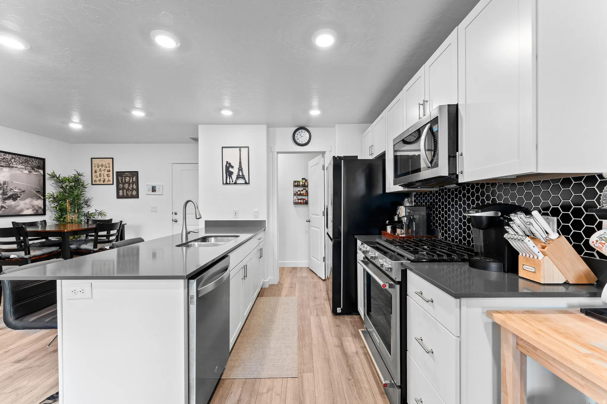 Contemporary kitchen featuring white cabinetry, dark countertops, and a black hexagonal tile backsplash