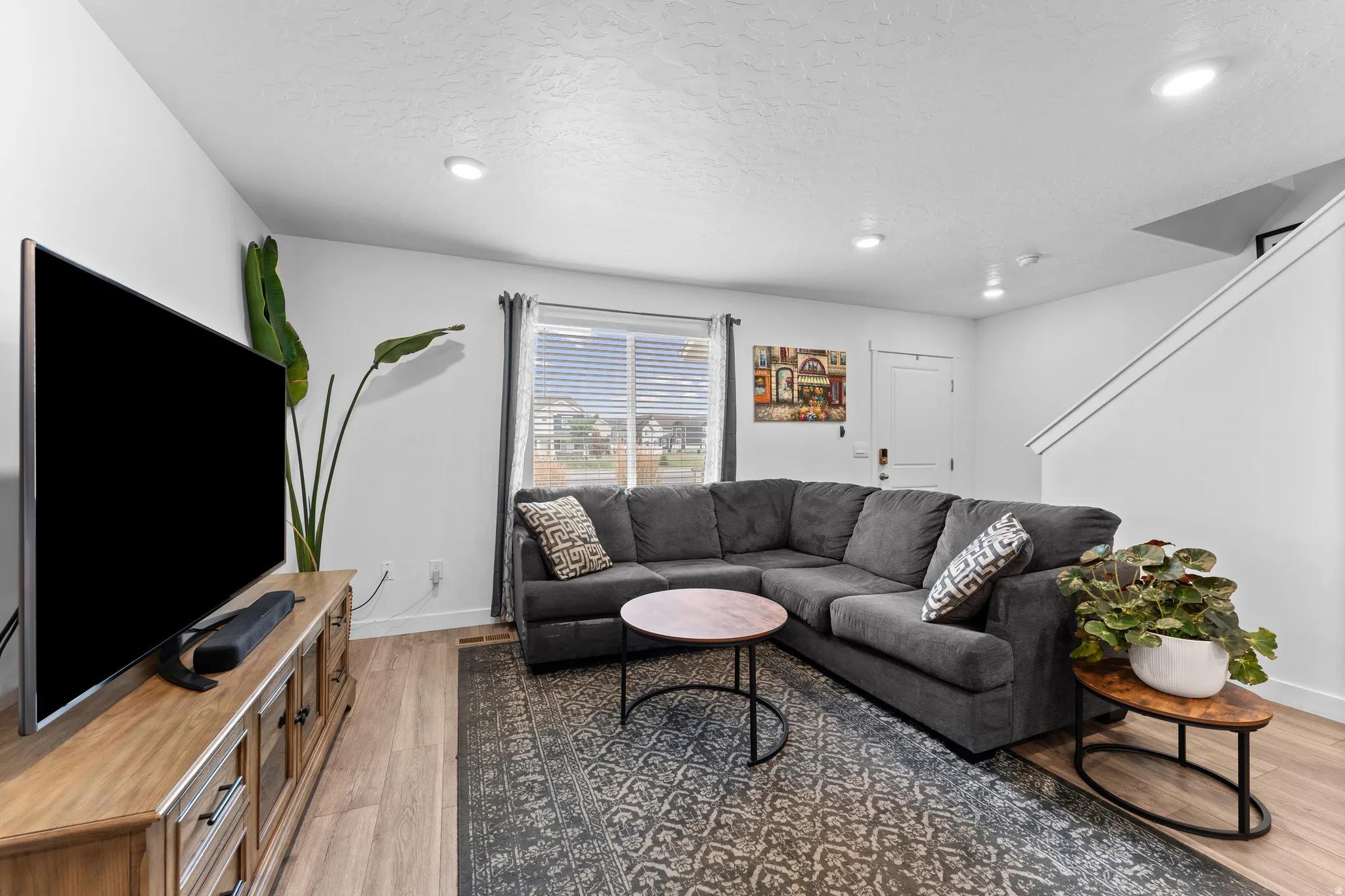 Open concept living space featuring wood-finish flooring, recessed lighting, a window with blinds, and white painted walls