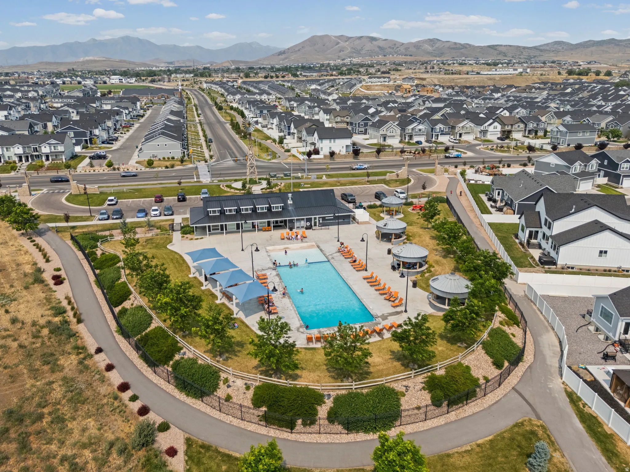 Community amenities featuring a rectangular swimming pool, multiple shaded cabanas, and a dedicated clubhouse building