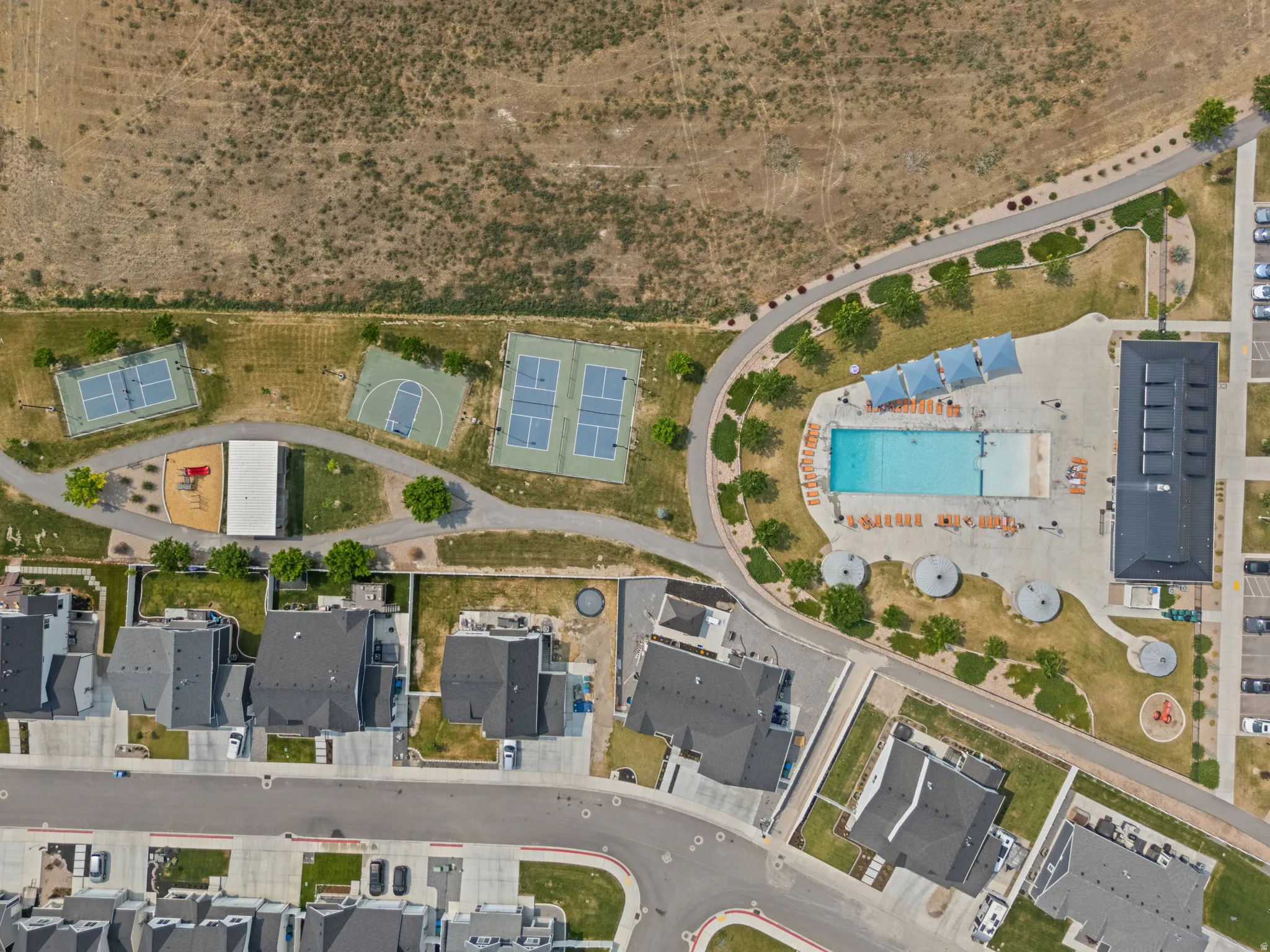 Aerial view showcasing a community pool, tennis courts, basketball court, and playground equipment