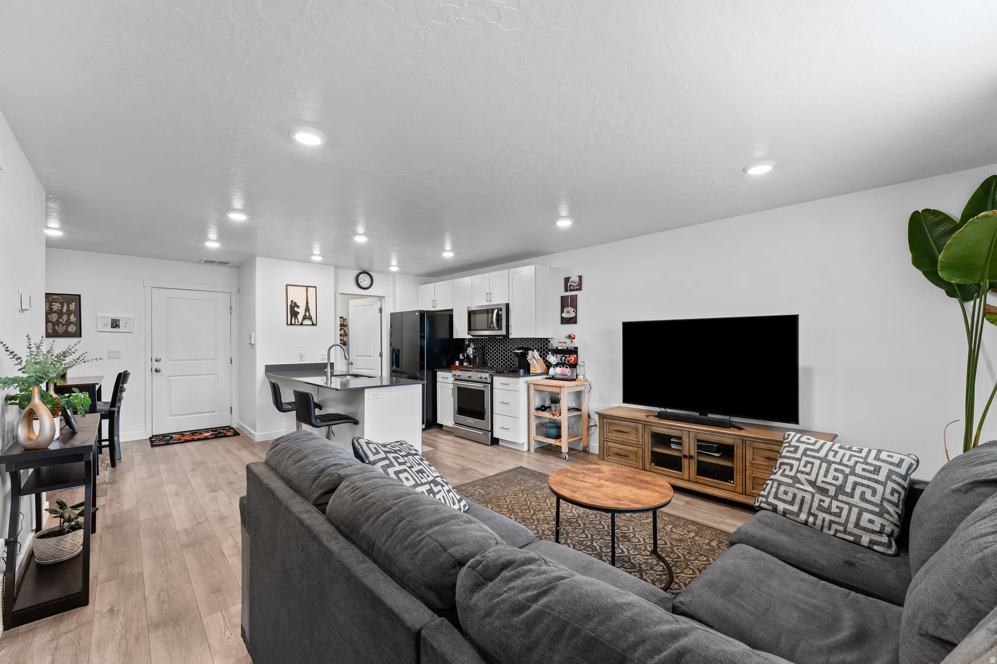 Open-concept living space featuring wood-finish flooring, recessed lighting, and a white color palette