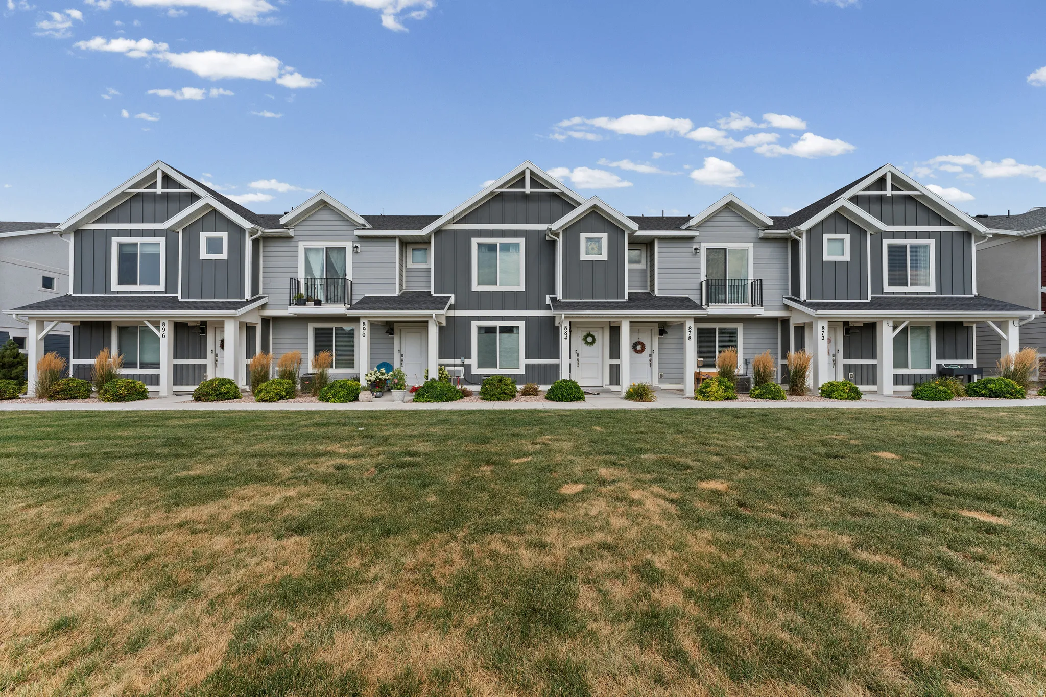 Row of townhomes featuring contrasting light and dark gray siding, white trim, and covered front porches