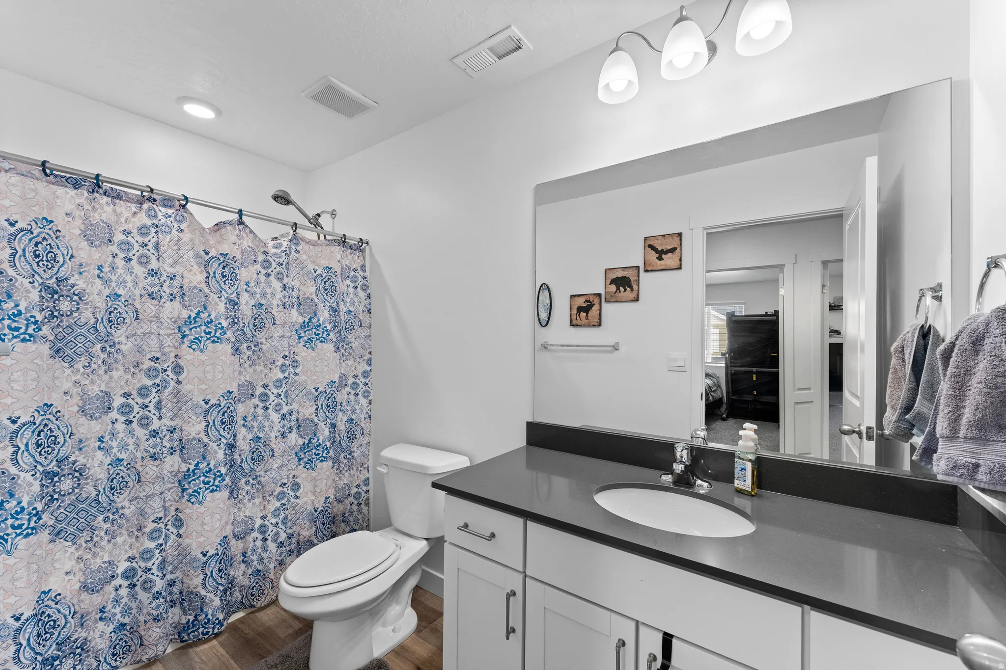 Modern bathroom featuring a single vanity with a dark countertop, an undermount sink, and a chrome faucet