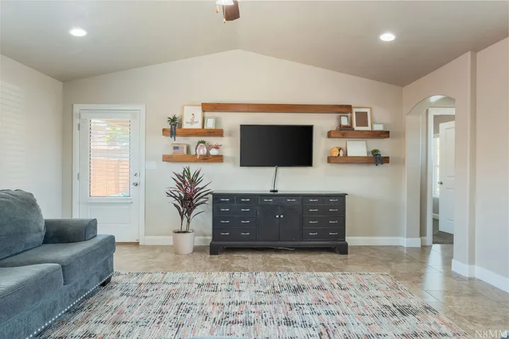 Vaulted ceiling living space featuring tile flooring and recessed lighting
