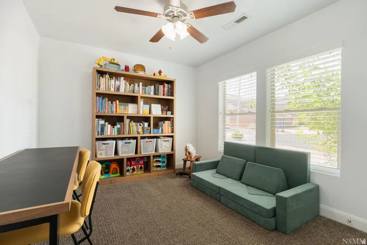 Well-lit room featuring neutral-toned carpeting and white walls