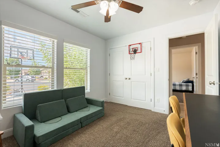 Room with twin windows featuring horizontal blinds, a ceiling fan with light fixture, and neutral carpet flooring