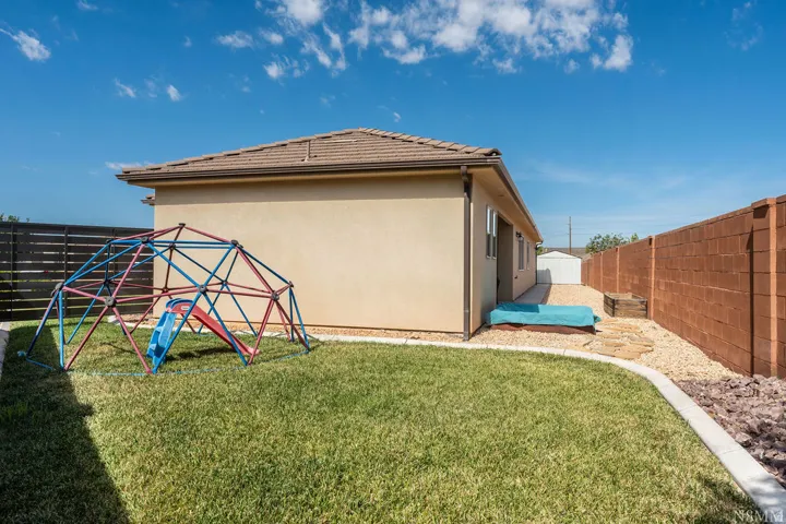 Spacious backyard with a manicured lawn, concrete curbing, and a gravel perimeter