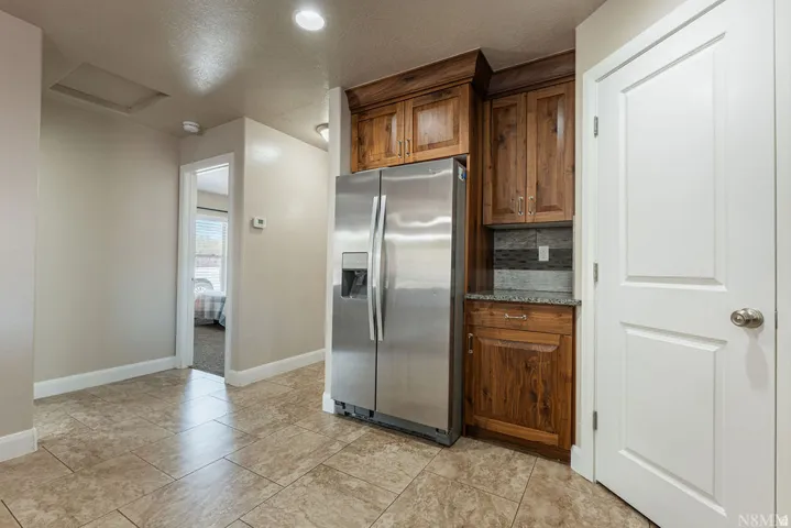 Stainless steel refrigerator with a water and ice dispenser, surrounded by wood-finish cabinetry