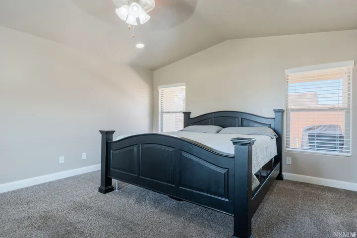 Carpeted room featuring a vaulted ceiling with a ceiling fan, recessed lighting, and two windows with blinds