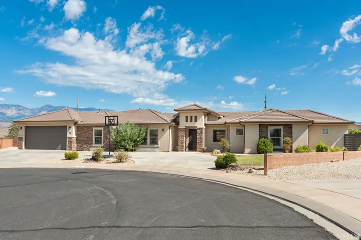 Single-story stucco exterior with stone accents, a tile roof, a two-car garage, and a concrete driveway