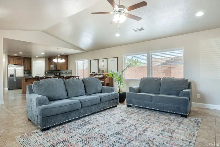 Open-concept living space featuring vaulted ceilings, recessed lighting, and tile flooring
