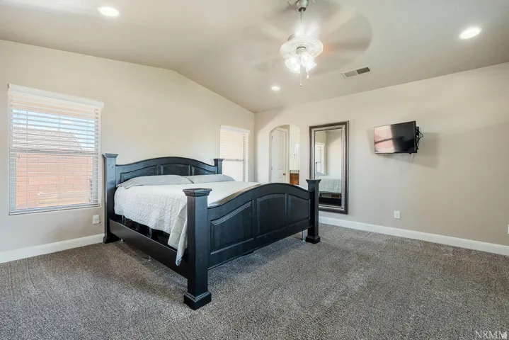 Spacious room featuring vaulted ceilings, recessed lighting, and soft grey carpeting