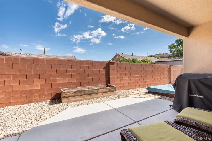 Covered patio area featuring a concrete slab, gravel landscaping, and a built-in wood planter box