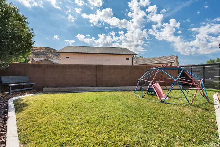 Spacious backyard featuring a manicured lawn, concrete block perimeter wall, and integrated concrete curbing