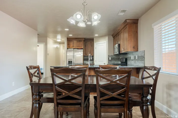Dining area featuring a dark wood-finish dining table with matching chairs, an overhead chandelier, and tile flooring