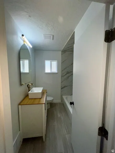 Bathroom featuring a freestanding white vanity with a wood-finish countertop and vessel sink