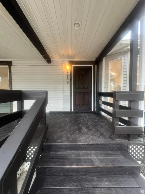 Covered porch with dark-stained wood-finish flooring, steps, and railings