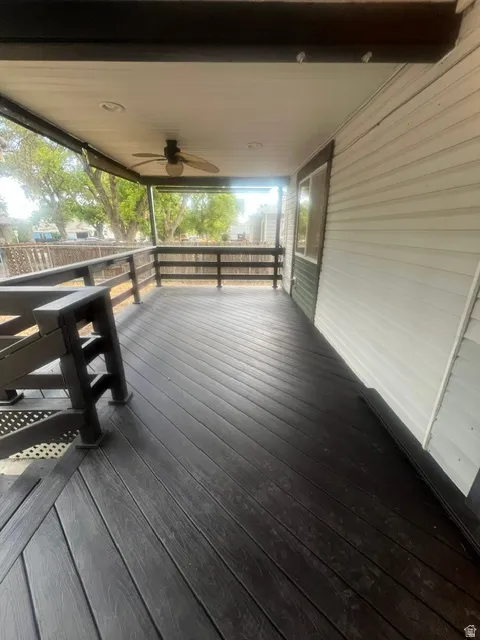 Covered outdoor deck with wood-finish decking, dark railings, and a ceiling fan