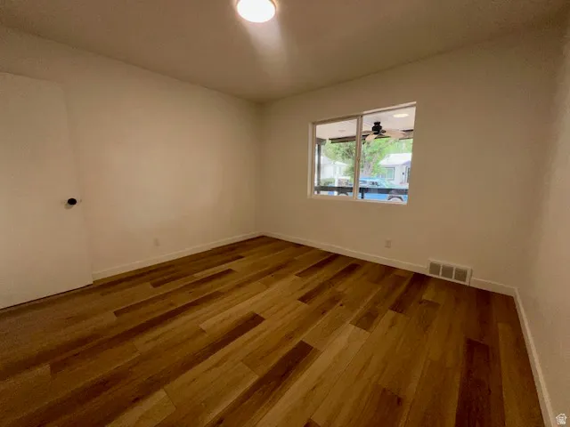 Spacious primary room featuring wood-finish flooring, white baseboards, and a single window