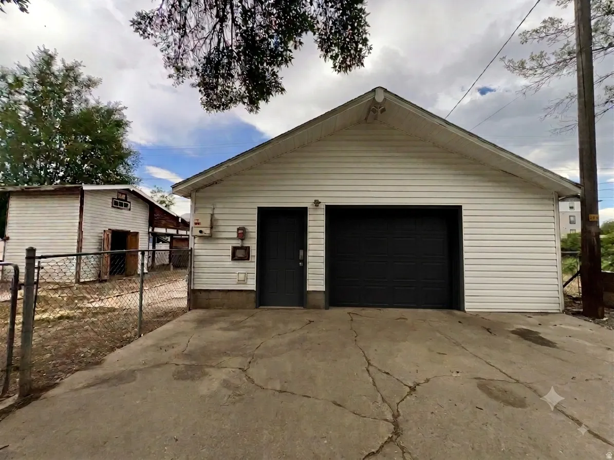 Detached garage featuring white horizontal siding, a dark garage door, and a separate dark entry door