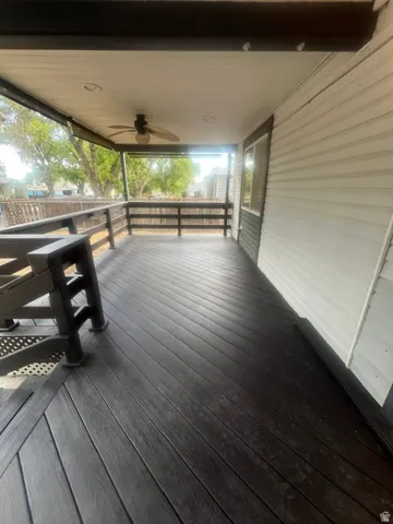 Covered outdoor deck with wood-finish decking, dark railings, and a ceiling fan