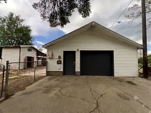 Detached garage featuring white horizontal siding, a dark garage door, and a separate dark entry door