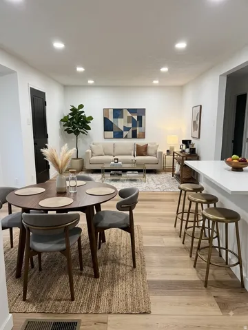 staged room Recessed lighting, wood-finish flooring, white walls, and a kitchen island with seating