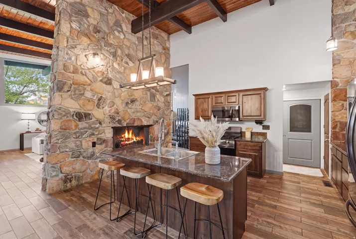 Great room featuring a floor-to-ceiling stone fireplace, vaulted wood-beam ceiling