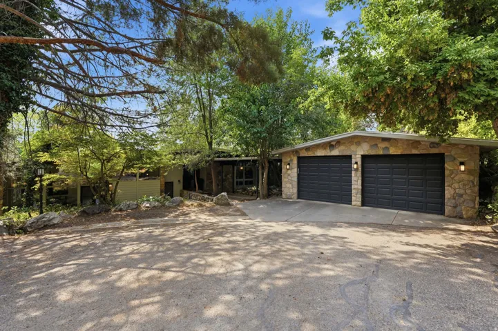Stone-clad garage featuring two dark paneled doors and exterior lighting fixtures