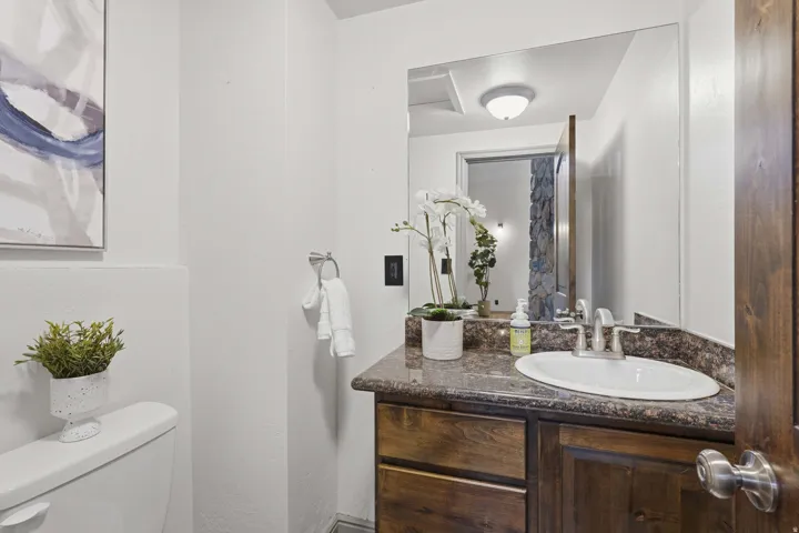 Half bathroom vanity with a dark wood-finish cabinet, countertop with integrated sink, and an expansive wall mirror