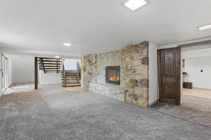 Stone-clad fireplace with a hearth and a built-in firebox, set against carpet flooring